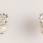 Image of silver earrings with a knot design. The purpose of this image is to highlight the earrings by Alma Jewelry.