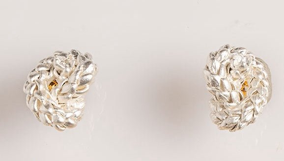 Image of silver earrings with a knot design. The purpose of this image is to highlight the earrings by Alma Jewelry.