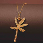 Gold palm tree necklace on a dark brown background