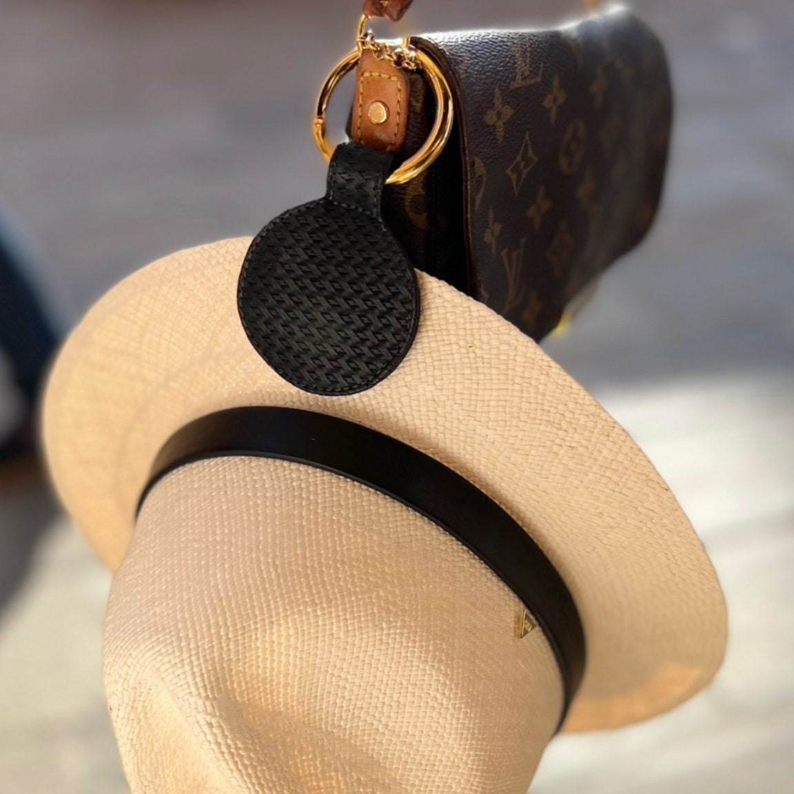 Black hat pendant with a straw hat design hanging from a bag.