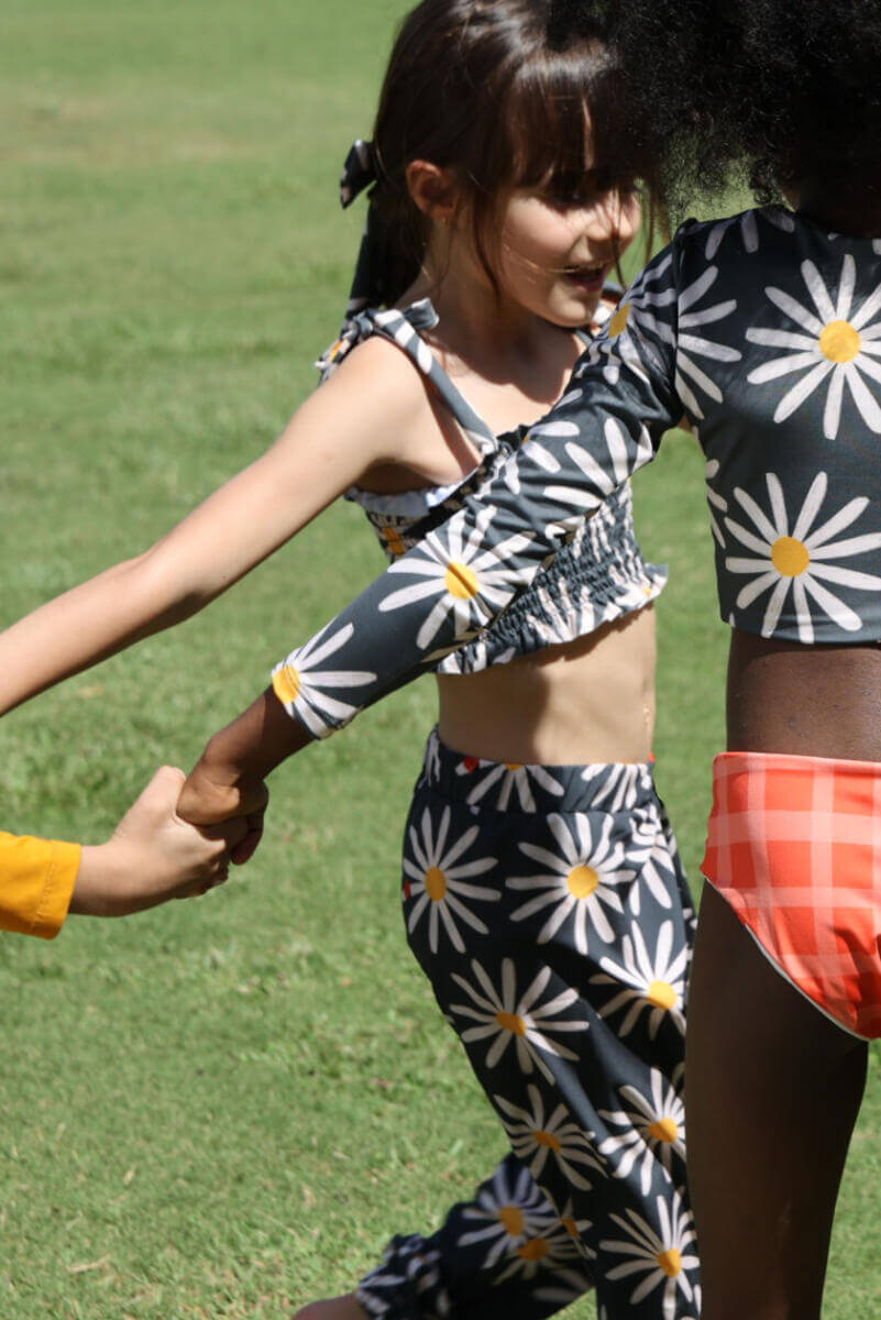 kids holding hands dancing in grass. One little girl is wearing the picnic pants with a matching crop top.