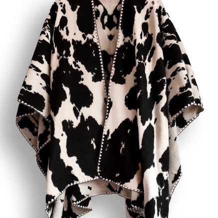 Black and white cow patterned poncho on a white background. 