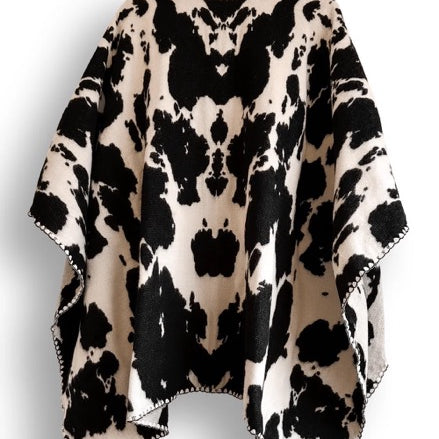 Black and white cow patterned poncho on a white background.