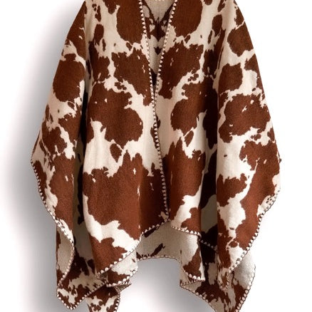Brown and white cow patterned poncho on a white background.