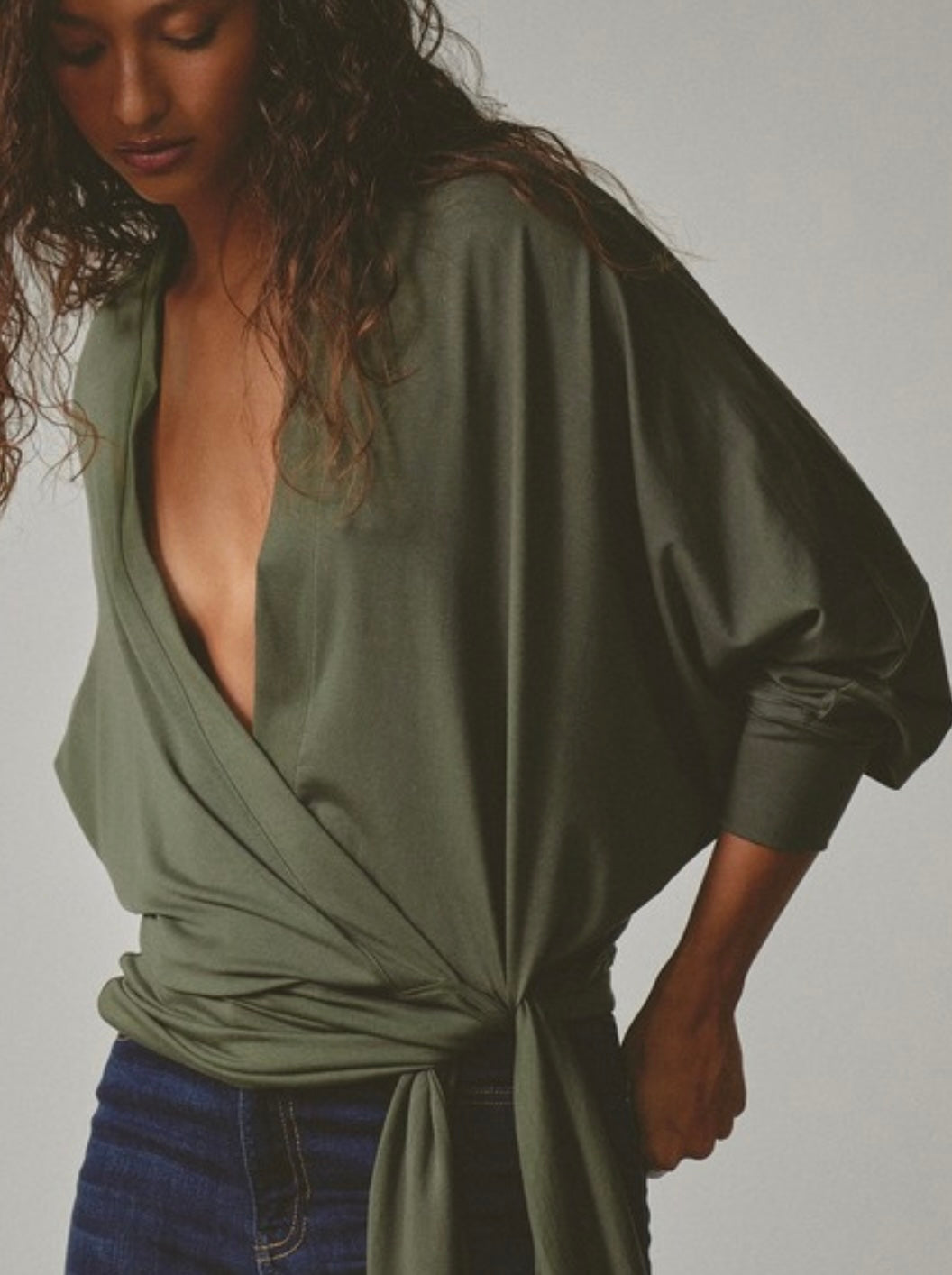 Woman wearing a green wrap top with a plain background