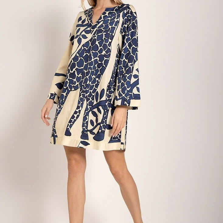 Model wearing a giraffe print cover-up dress with long sleeves. She's standing against a white background and looking at the camera. The purpose of this image is to highlight the dress.