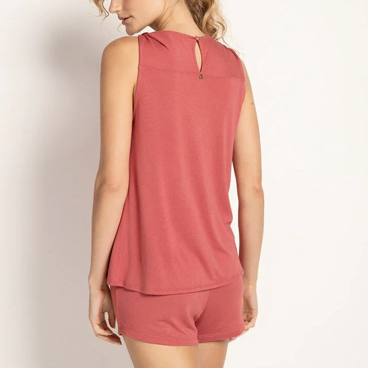 Model wearing a rose colored pajama set. The top is sleeveless. She's looking to the side and showing her back. She's in front of a white wall. The purpose of this image is to highlight the clothing.