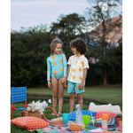 Example of the brother and sister matching look. The little girl is wearing the sun longsleeve bikini. He is wearing the sun guayabera along with these sun swim trunks. They are standing over an picnic setup at a park.