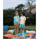 Example of the brother and sister matching look. The little girl is wearing the sun longsleeve bikini. He is wearing the sun guayabera along with these sun swim trunks. They are standing over an picnic setup at a park.