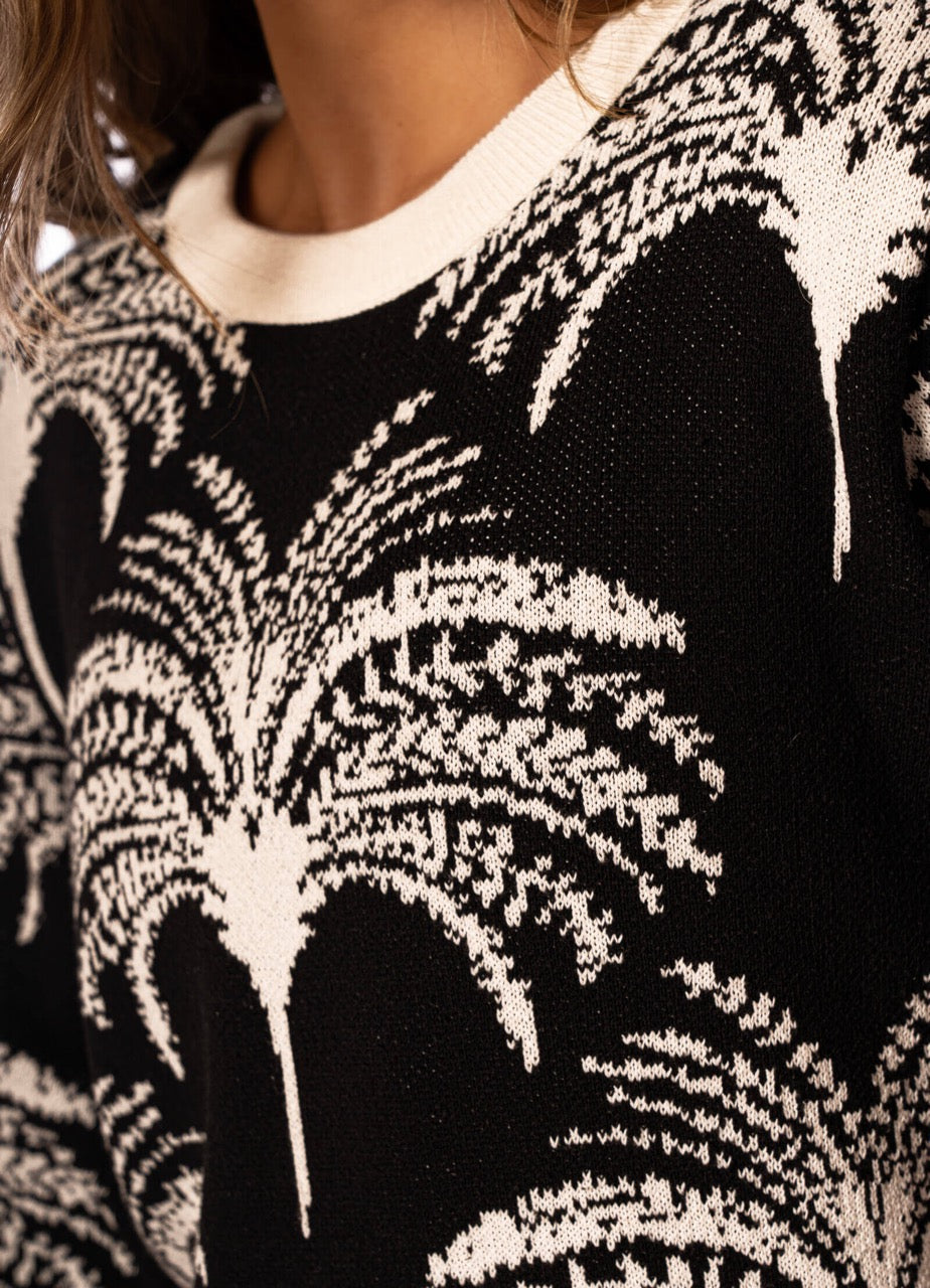 Close-up of a black and white tree palm patterned sweater.