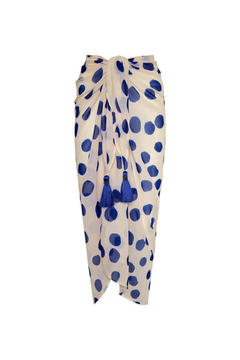Image of a white sarong with blue polka dots. It's tied as it would be on a body. It's against a white background. The purpose of this image is to highlight the sarong, which is on sale at EVAMAIA boutique in Studio City.