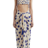 Woman wearing a bikini top with blue polka dots and a matching sarong. She's standing behind a white background. The purpose of this image is to highlight the sarong by Encantadore Swimwear.