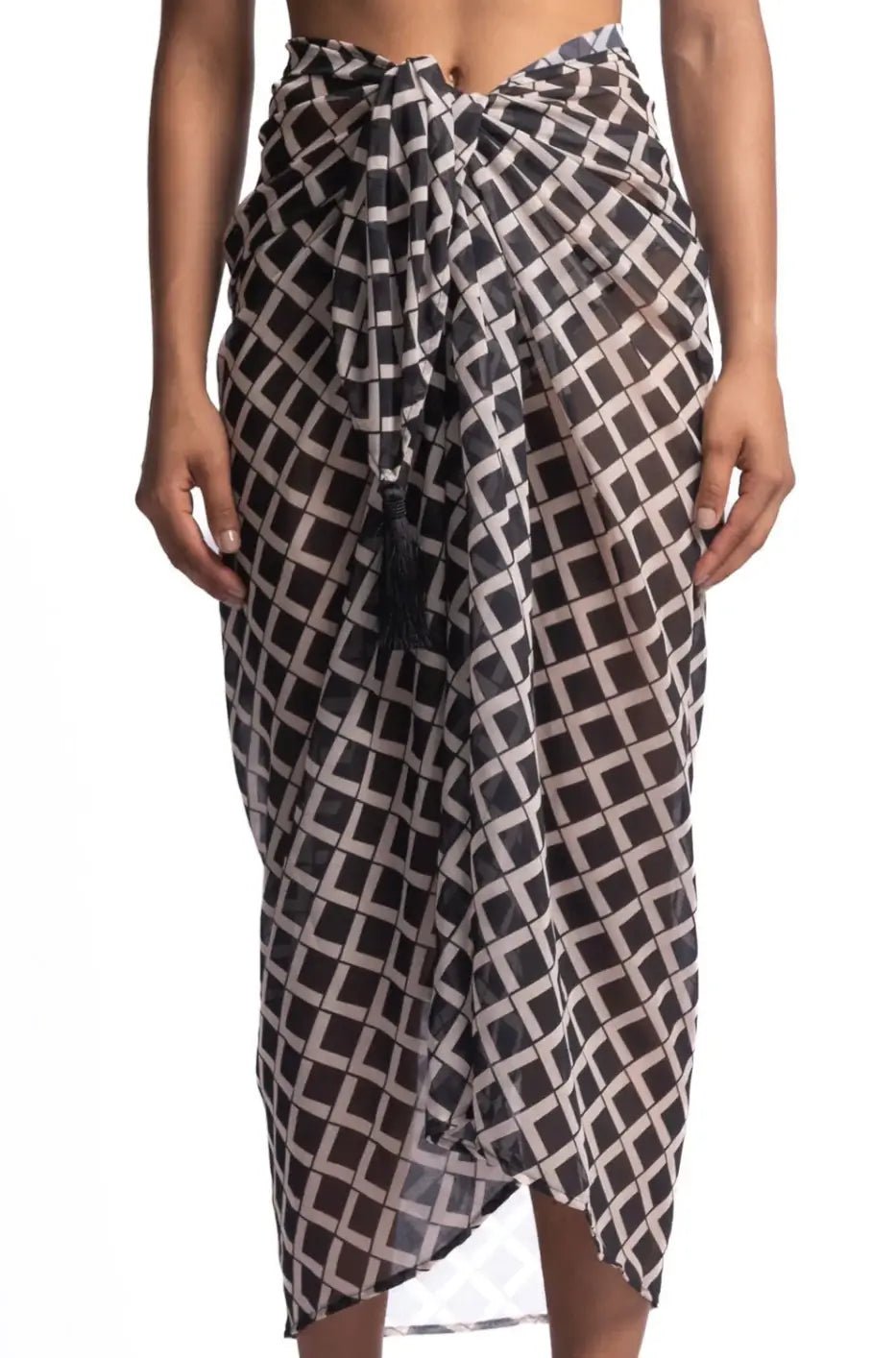 Close up image of a woman wearing a black and white sarong. She's standing behind a white background. The purpose of this image is to highlight the sarong by Encantadore Swimwear.