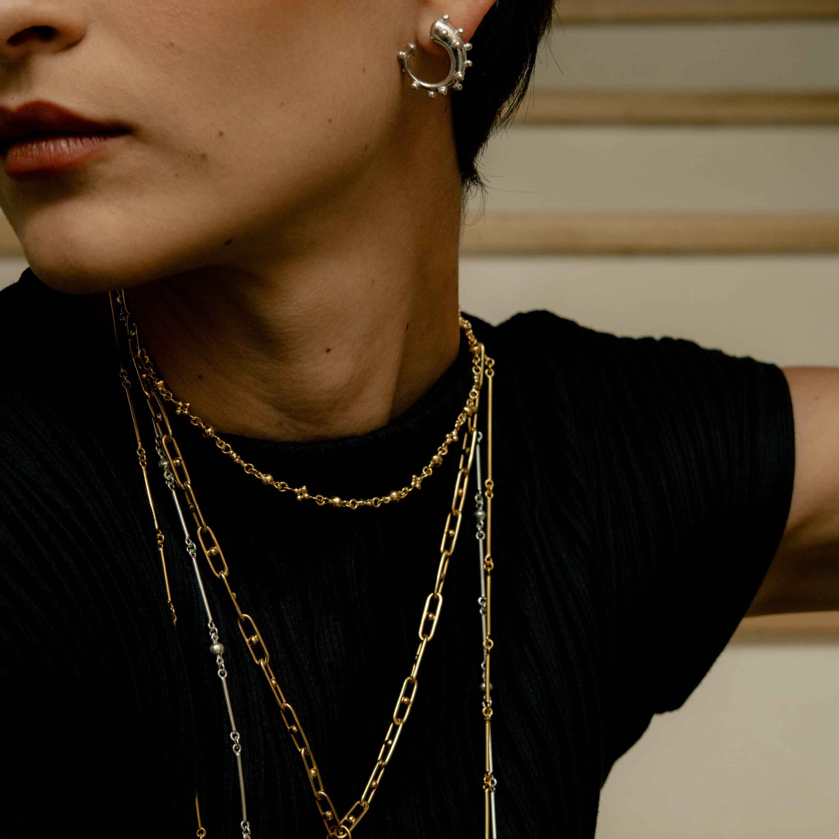 Woman wearing reclaimed sterling silver mini hoops with sphere trim and many necklaces, handcrafted in Bogotá, Colombia