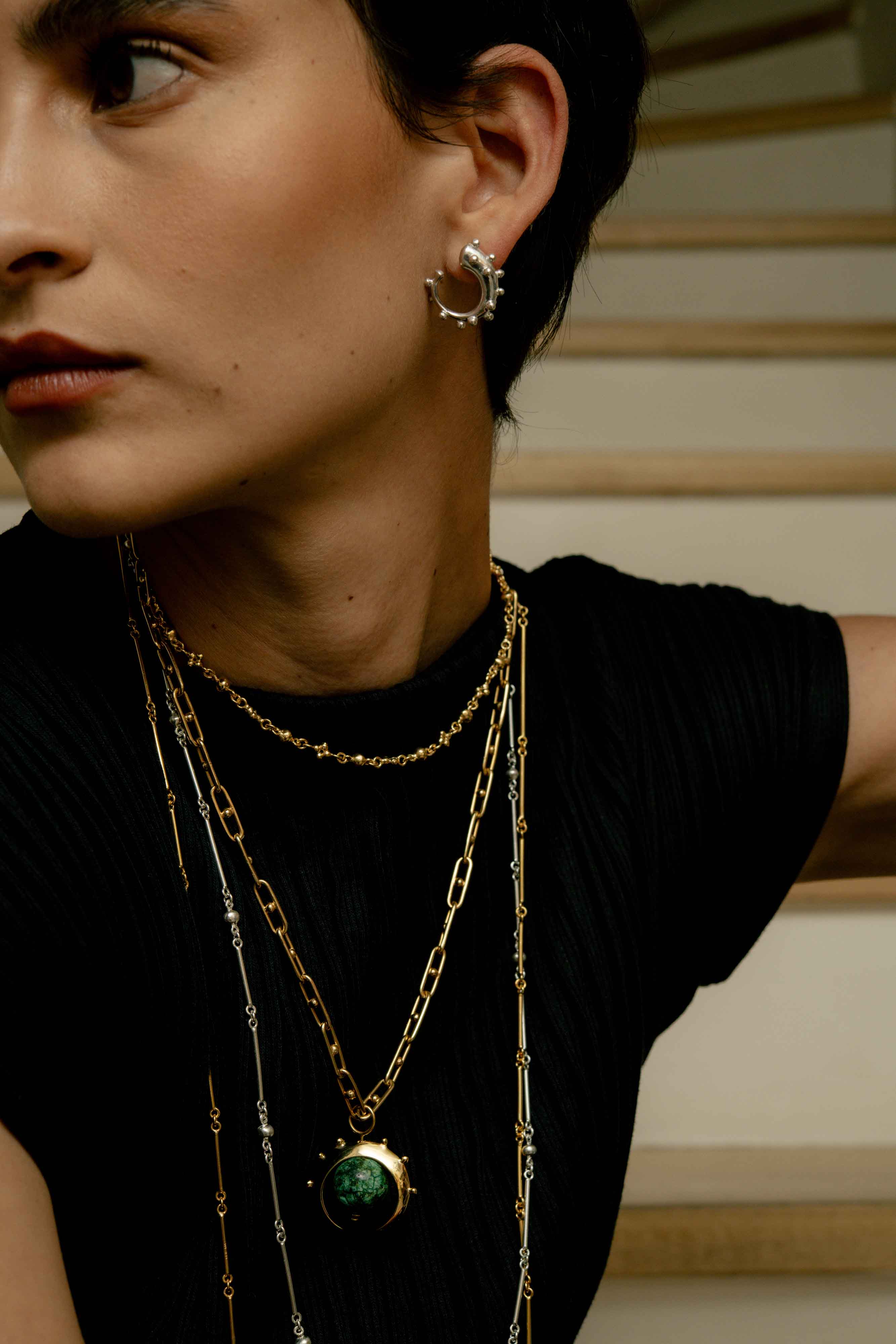 Woman wearing reclaimed sterling silver mini hoops with sphere trim and many necklaces, handcrafted in Bogotá, Colombia