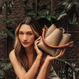 Image of a woman holding the Tulip Baletti leather handbag in grey and camel. The purpose of the image is to highlight the bag because it is for sale at EVAMAIA boutique in Studio City, CA and online.