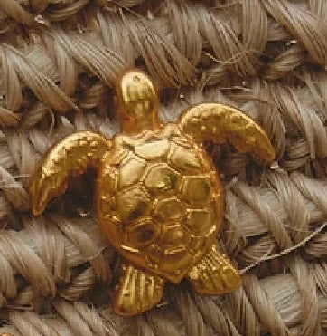 Gold turtle pendant on a textured beige background