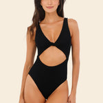 Woman wearing a black cut-out swimsuit on a beige background
