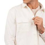 Close up of a man wearing a t-shirt and a white cotton jacket. He's standing behind a white background. The purpose of this image is to highlight the jacket, which is made in Colombia and available at EVAMAIA boutique.
