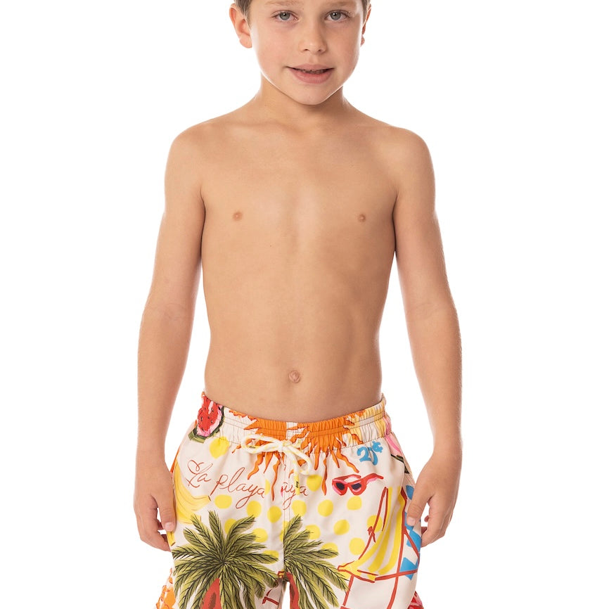 Young boy wearing colorful tropical-themed swim shorts on a white background