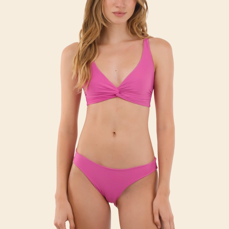 Woman wearing a pink bikini set on a beige background