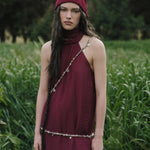 Woman in a burgundy dress and headscarf standing in a field