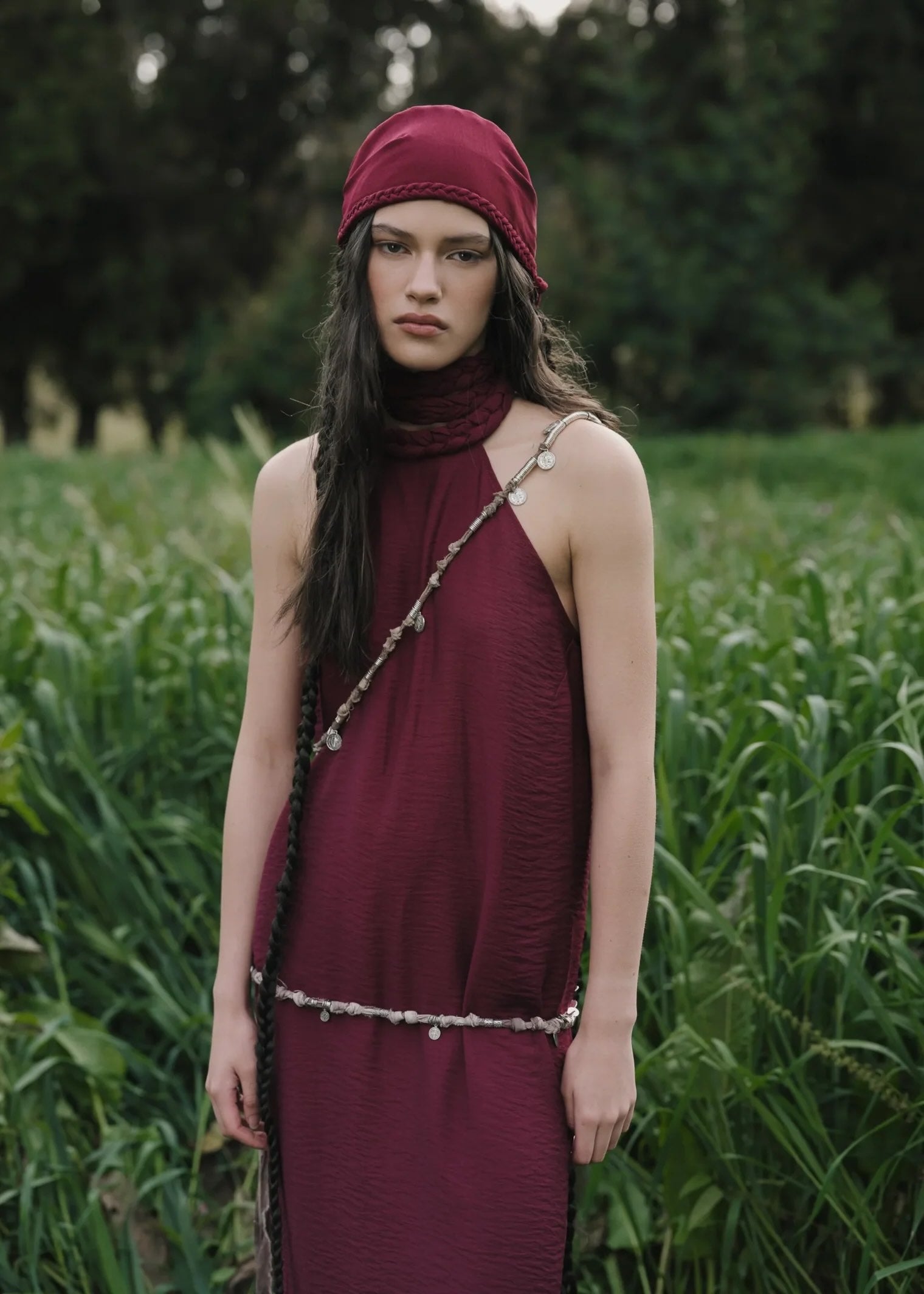 Woman in a burgundy dress and headscarf standing in a field
