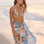 Image of a woman wearing a blue bikini and matching beachwrap on her waist. The purpose of the image is to highlight the beach cover-up by Flor Amazona.