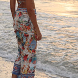 Image of a woman wearing a blue bikini and matching beachwrap on her waist. The purpose of the image is to highlight the beach cover-up by Flor Amazona.