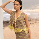 Woman wearing a yellow and brown patterned outfit on a beach.