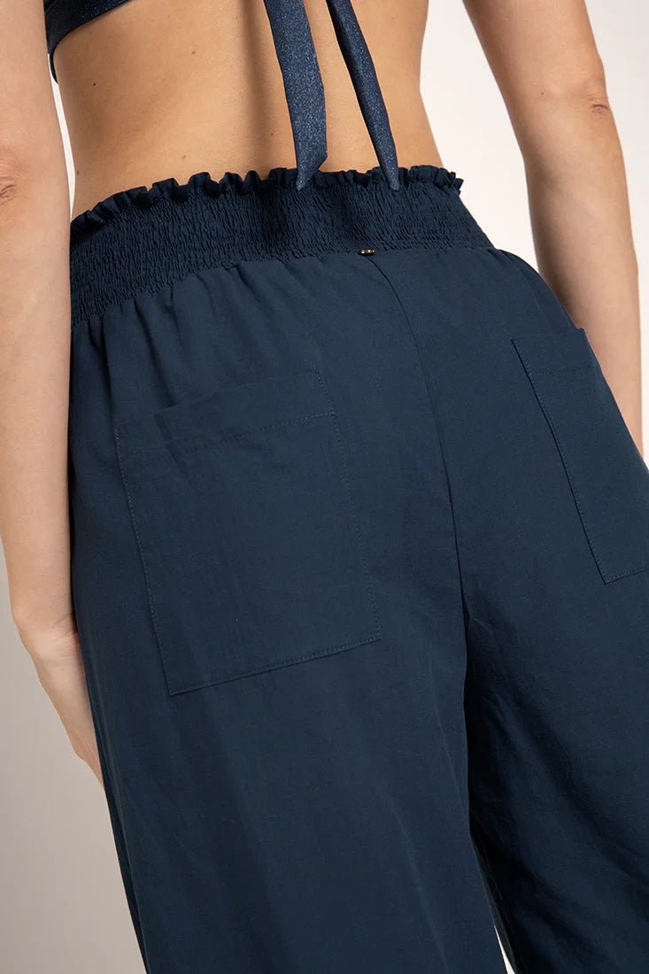 Close up image of a woman wearing wide leg pants. The purpose of this image is to highlight the back pockets on the pants.