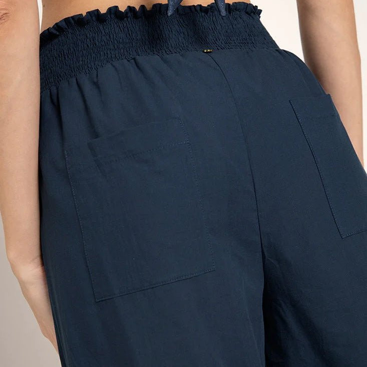 Close up image of a woman wearing wide leg pants. The purpose of this image is to highlight the back pockets on the pants.