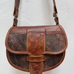 Brown leather handbag with cowhide pattern on a light gray background