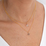 Close up image of a woman's neckline. She's wearing two necklaces. One has a charm of a Pisces zodiac sign and the other has a Fluorite stone. The purpose of this image is to highlight the necklaces, which are made in Colombia and sold in Studio City, at EVAMAIA boutique.