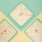 Image of two necklaces in a square package. One of the necklaces has a Scorpio Zodiac Sign. The other has a Laborite stone charm. The purpose of this image is to highlight the necklaces, which are for sale at EVAMAIA boutique in Studio City, CA.