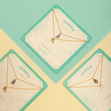 Image of two necklaces in a square package. One of the necklaces has a Scorpio Zodiac Sign. The other has a Laborite stone charm. The purpose of this image is to highlight the necklaces, which are for sale at EVAMAIA boutique in Studio City, CA.