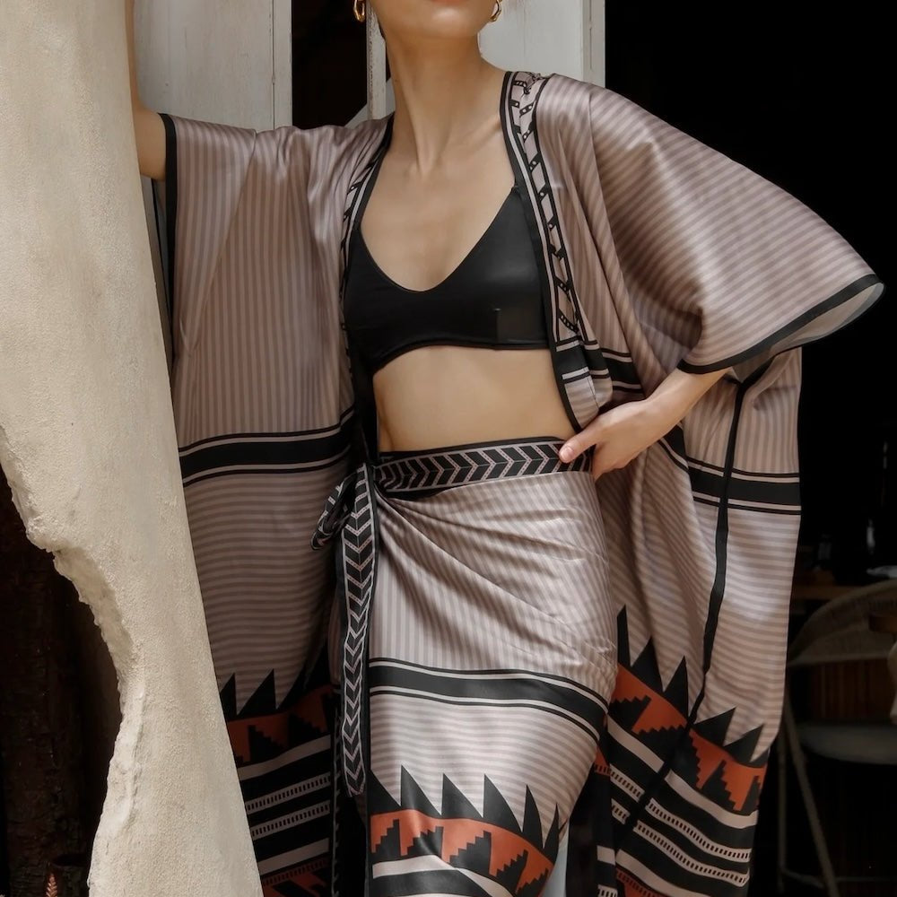 Woman wearing the Apache Kimono and a bathing suit top with the Apache wrap skirt. All available at EVAMAIA.