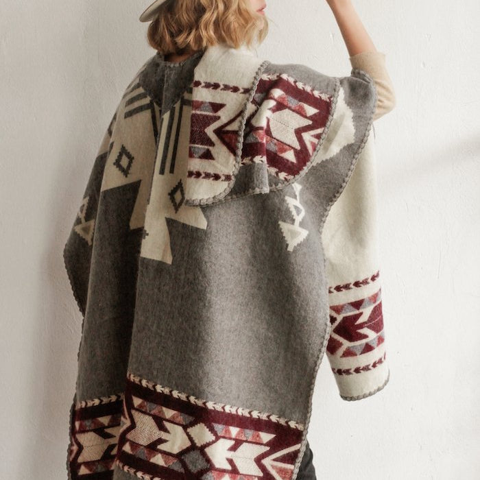 Back view of a woman wearing the Aras Poncho in Grey and Burgundy by Plisse.