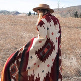 Frontera Reversible Throw Blanket draped over model. She styled it with a light brown hat. She is using the blanket outside on a field of plains.