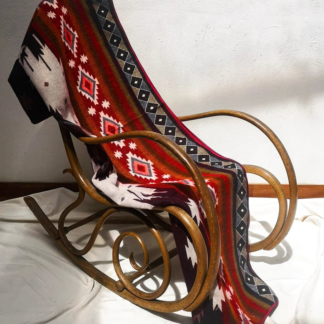 Frontera Reversible Throw Blanket draped over a classic wooden rocking chair.