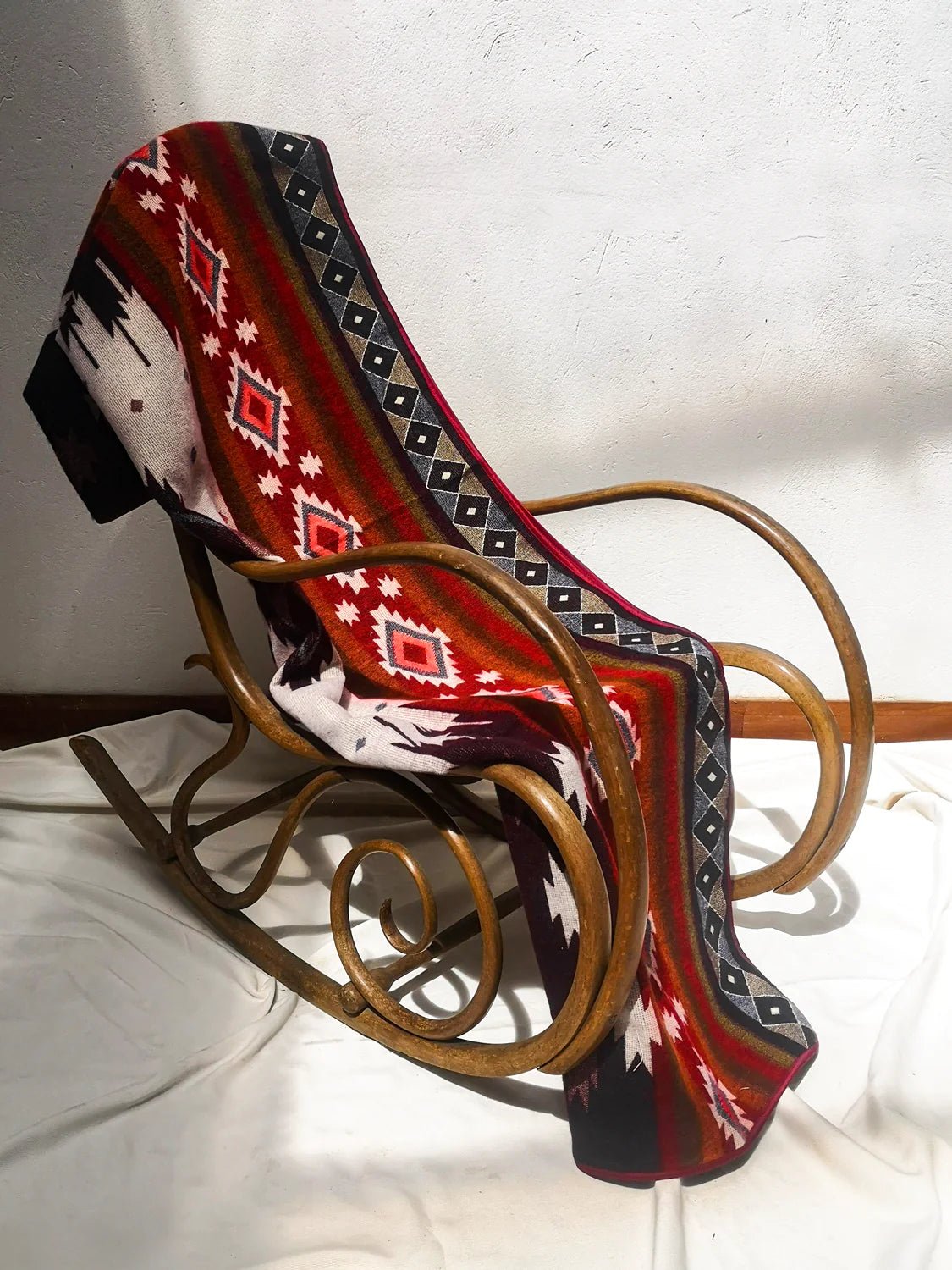 Frontera Reversible Throw Blanket draped over a classic wooden rocking chair.