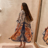 Model wearing the Kimono Bengal Tiger. She is towards the wall with a large mirror next to her. The design features a mirrored design of a large tree, nature details, and the bengal tiger.