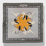 La Gaitana Scarf by Plissé. Image of 8 Cacica Gaitana in a circle over a yellow dot. The whole deign over over a light grey geometric pattern with a frame like border and arrow border. The overall tone of the scarf is a washed out grey. 