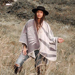 Paloma wearing grey natura poncho standing in the middle of plains.