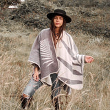 Paloma wearing grey natura poncho standing in the middle of plains.