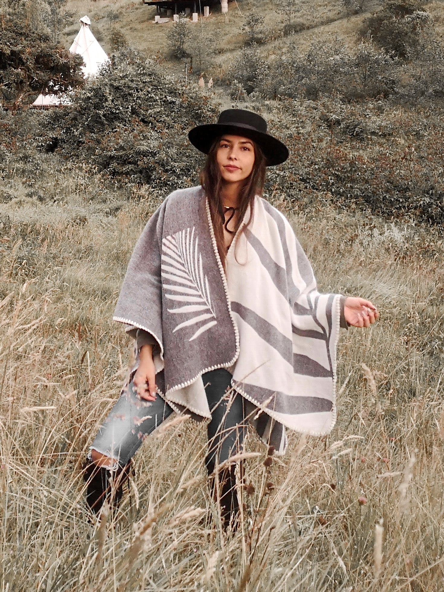 Paloma wearing grey natura poncho standing in the middle of plains.