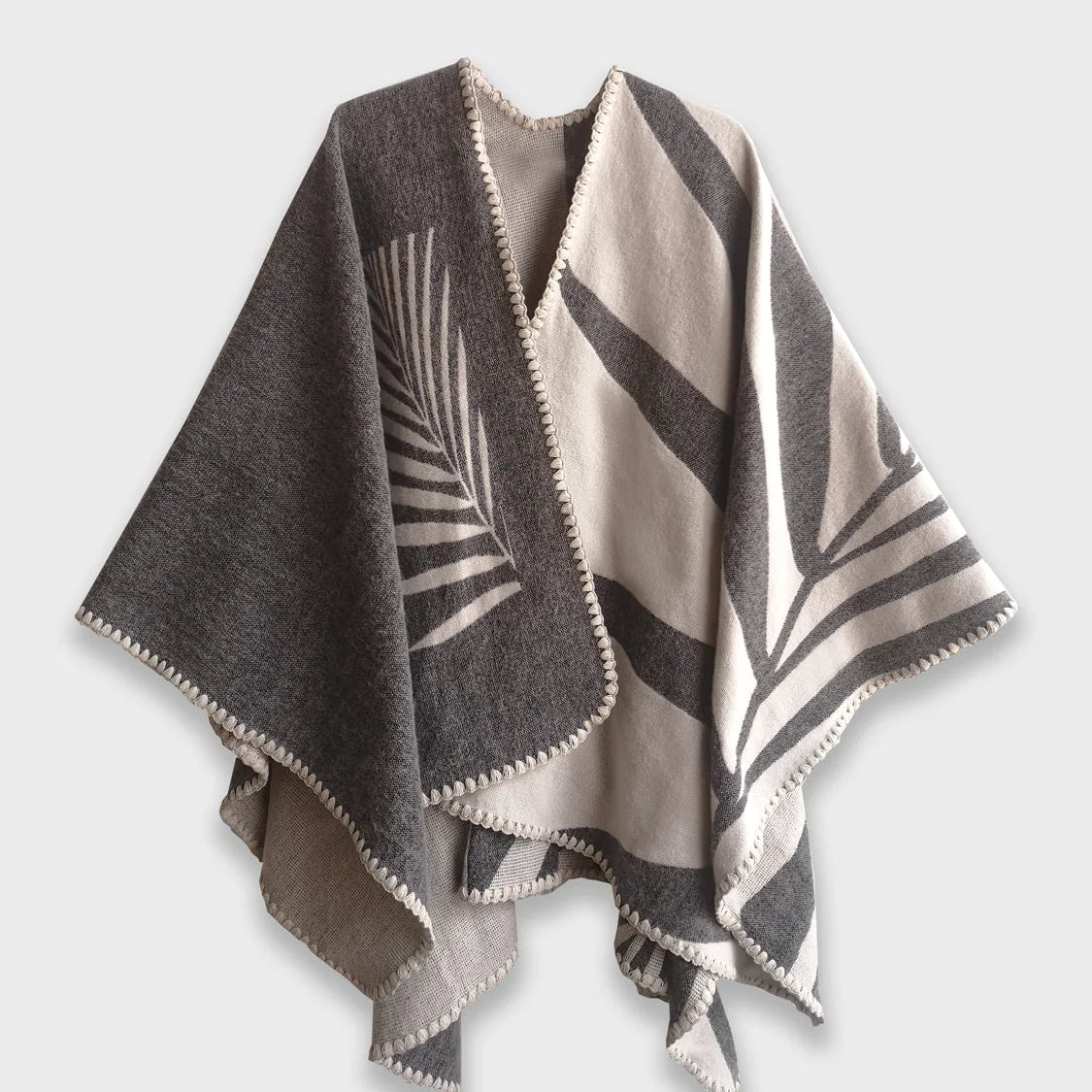 Grey Natura Poncho on a white background. This poncho features a color block design with leaflike pattern on the darker half. On the lighter half is ti just a small rectangle box of a leaf.