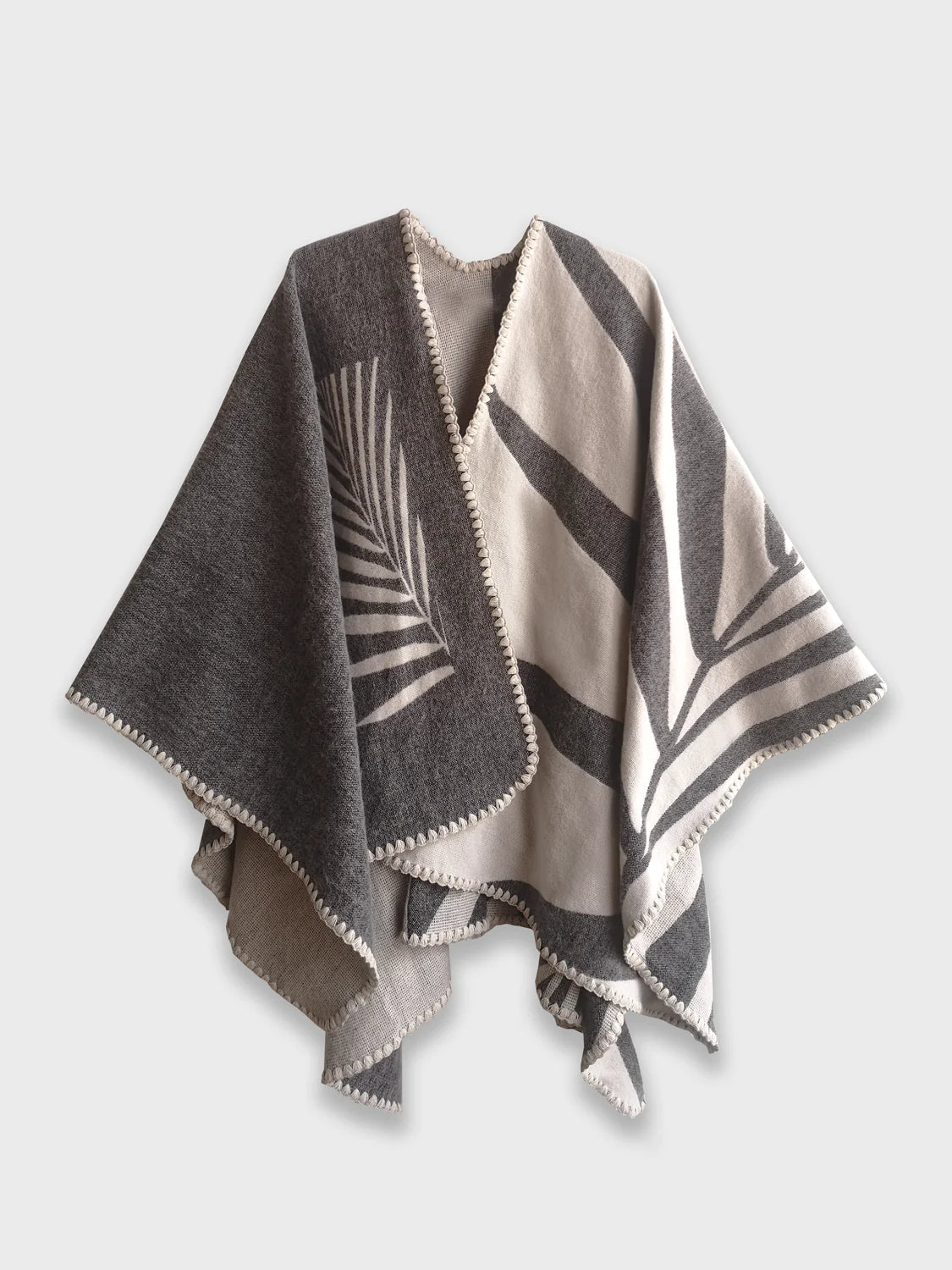 Grey Natura Poncho on a white background. This poncho features a color block design with leaflike pattern on the darker half. On the lighter half is ti just a small rectangle box of a leaf.