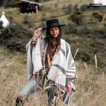 Paloma wearing grey natura poncho standing in the middle of plains.