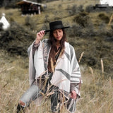 Paloma wearing grey natura poncho standing in the middle of plains.